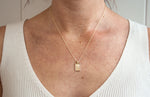 Load image into Gallery viewer, Model wearing AW Boutique&#39;s gold filled 16 inch dainty necklace with a tag pendant featuring a sunburst patterned effect. This option shows the 16-18 inch extendable length option, worn showing the 18 inch length option.  Part of the Celestial Collection. Gold filled jewellery.
