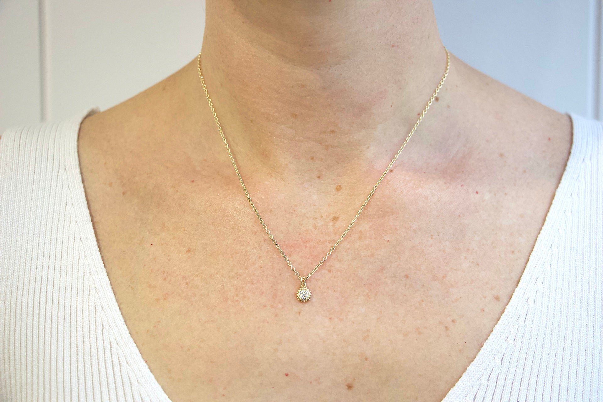 Model wearing AW Boutique's gold filled 16 inch dainty necklace with a mini Sun charm pendant. This option shows the 16-18 inch extendable length option, worn at 18 inches length in this image.  Part of Celestial collection. Gold filled jewellery. 