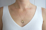 Load image into Gallery viewer, Model wearing AW Boutique&#39;s dual zodiac coin necklace featuring a dainty necklace chain, zodiac rustic coin charm, and your chosen star sign coin charm. Charms separated by a gold bead. Part of the Celestial Collection. Gold filled jewellery. Option shown is Taurus.
