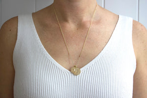 Model wearing AW Boutique's dual zodiac coin necklace featuring a dainty necklace chain, zodiac rustic coin charm, and your chosen star sign coin charm. Charms separated by a gold bead. Part of the Celestial Collection. Gold filled jewellery. Option shown is Taurus.