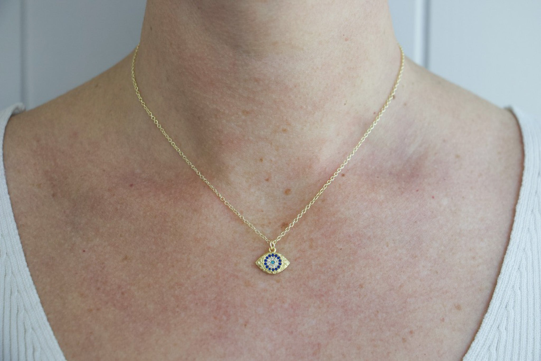 Model wearing AW Boutique gold filled jewellery. Evil Eye pendant charm on a dainty 16 inch fine cable necklace chain. Part of the Protection collection.