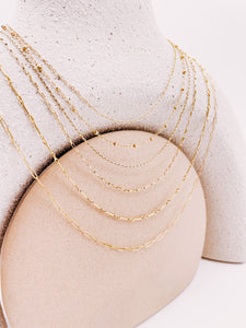 6 layering chains draped around a neck stand from AW Boutique gold filled jewellery.