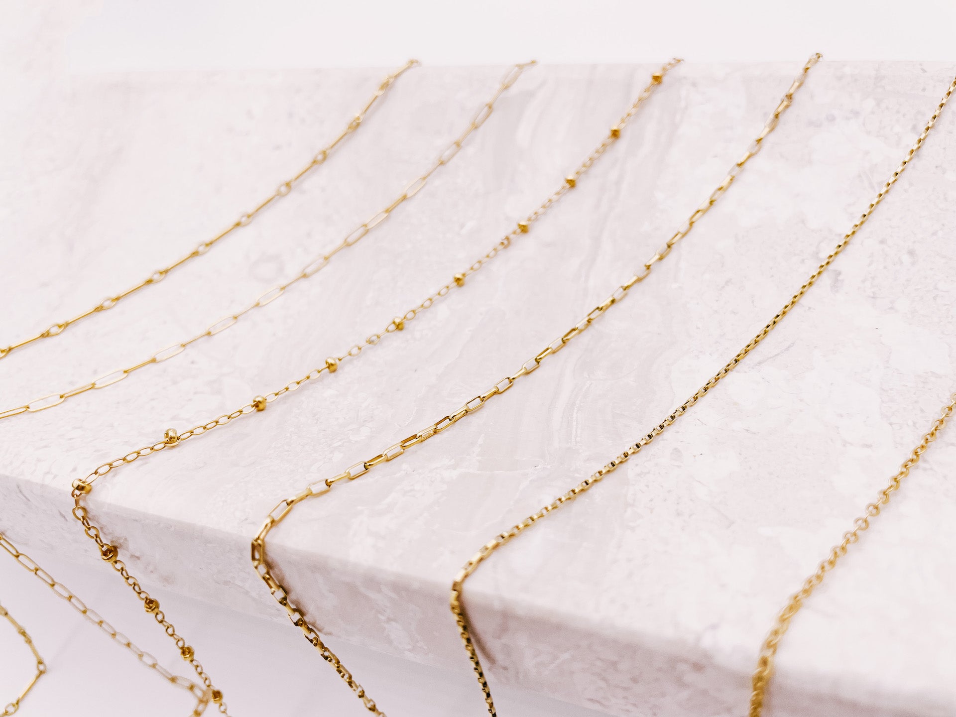 6 layering chains draped across a tray from AW Boutique gold filled jewellery.