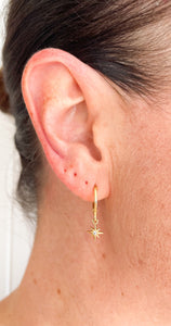 Mini north star shaped charm hanging from gold filled huggie earrings. Celestial jewellery.