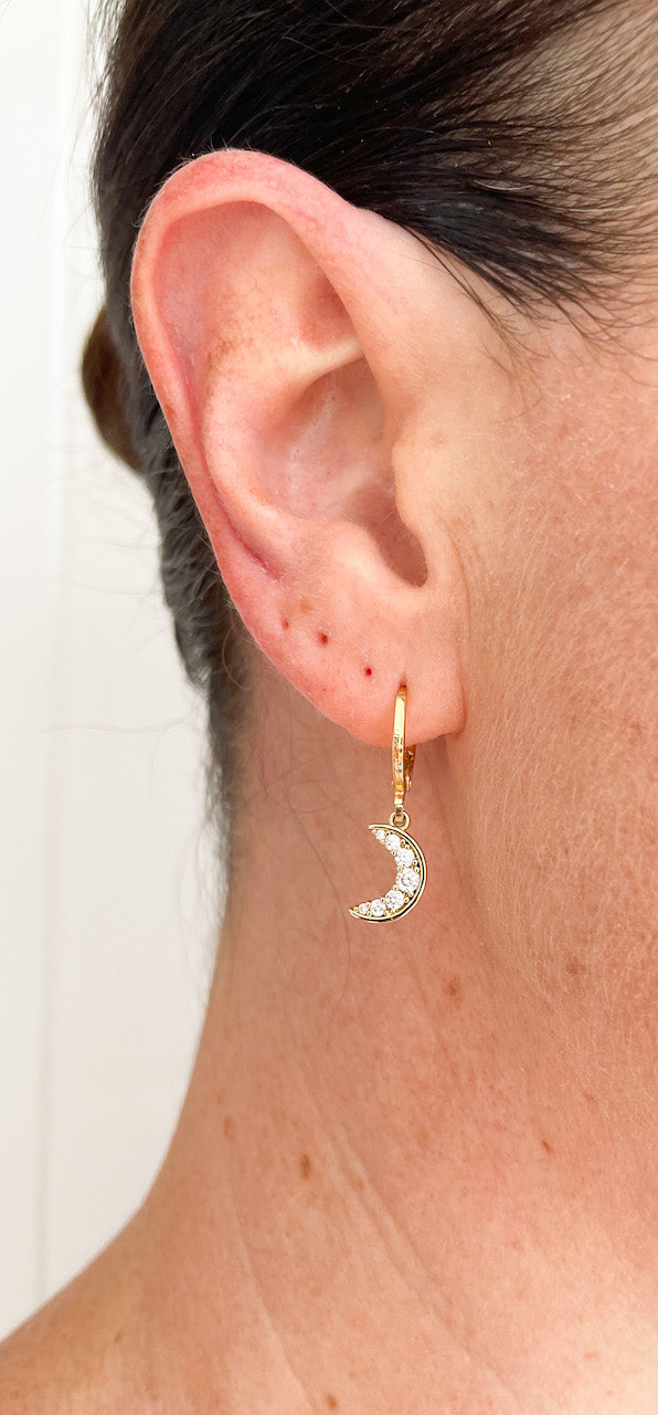 Mini crescent moon shaped charm hanging from gold filled huggie earrings. Celestial jewellery.