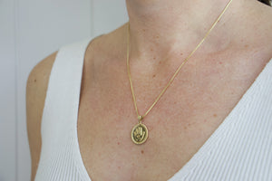 Model wearing AW Boutique's gold filled 18 inch box chain with a vintage looking Hamsa coin pendant. The Hamsa has small inscriptions and an evil eye on the hand. Pendant has rope effect edging. Part of Protection collection. Gold filled jewellery.