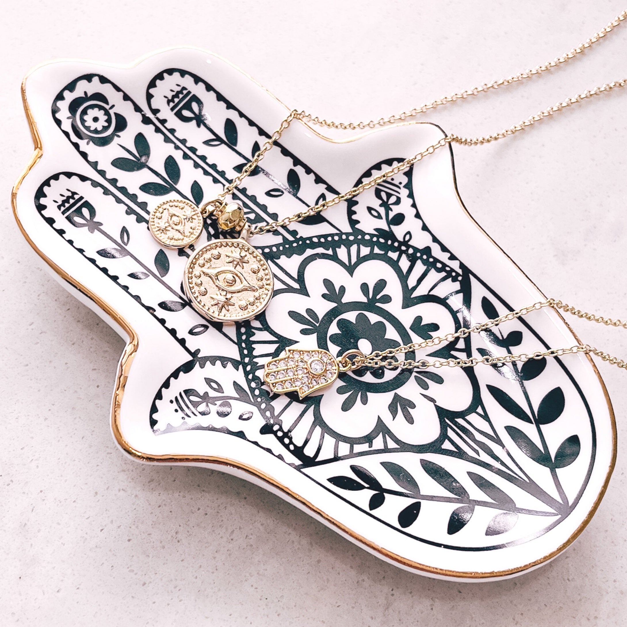 Hamsa Hand jewellery trinket tray from Australian jewellery brand AW Boutique.  Pictured with gold necklaces draped across the tray.