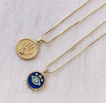 Load image into Gallery viewer, AW Boutique&#39;s gold filled 18 inch box chain with a vintage looking Hamsa coin pendant. The Hamsa has small inscriptions and an evil eye on the hand. Pendant has rope effect edging. Part of Protection collection. Gold filled jewellery.  This image shows the Vintage Hamsa Coin Necklace in a flat lay image with the Vintage Evil Eye Enamel Necklace.
